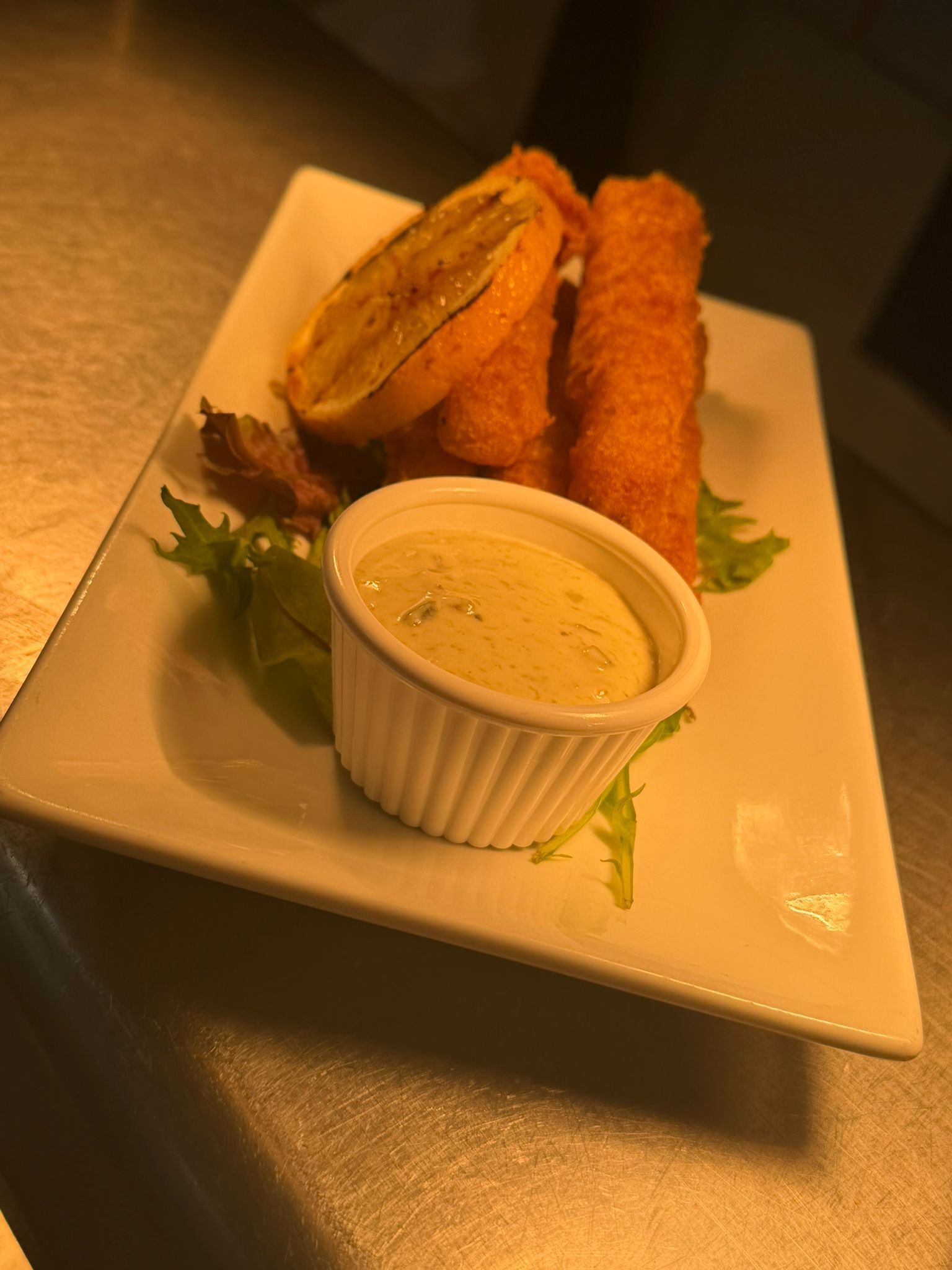 Un plato con un aperitivo enrollado, un cuenco pequeño de salsa y algunas verduras.
