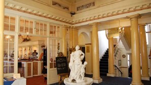 A grand lobby with a central fountain, large columns, and a staircase leading to upper floors.