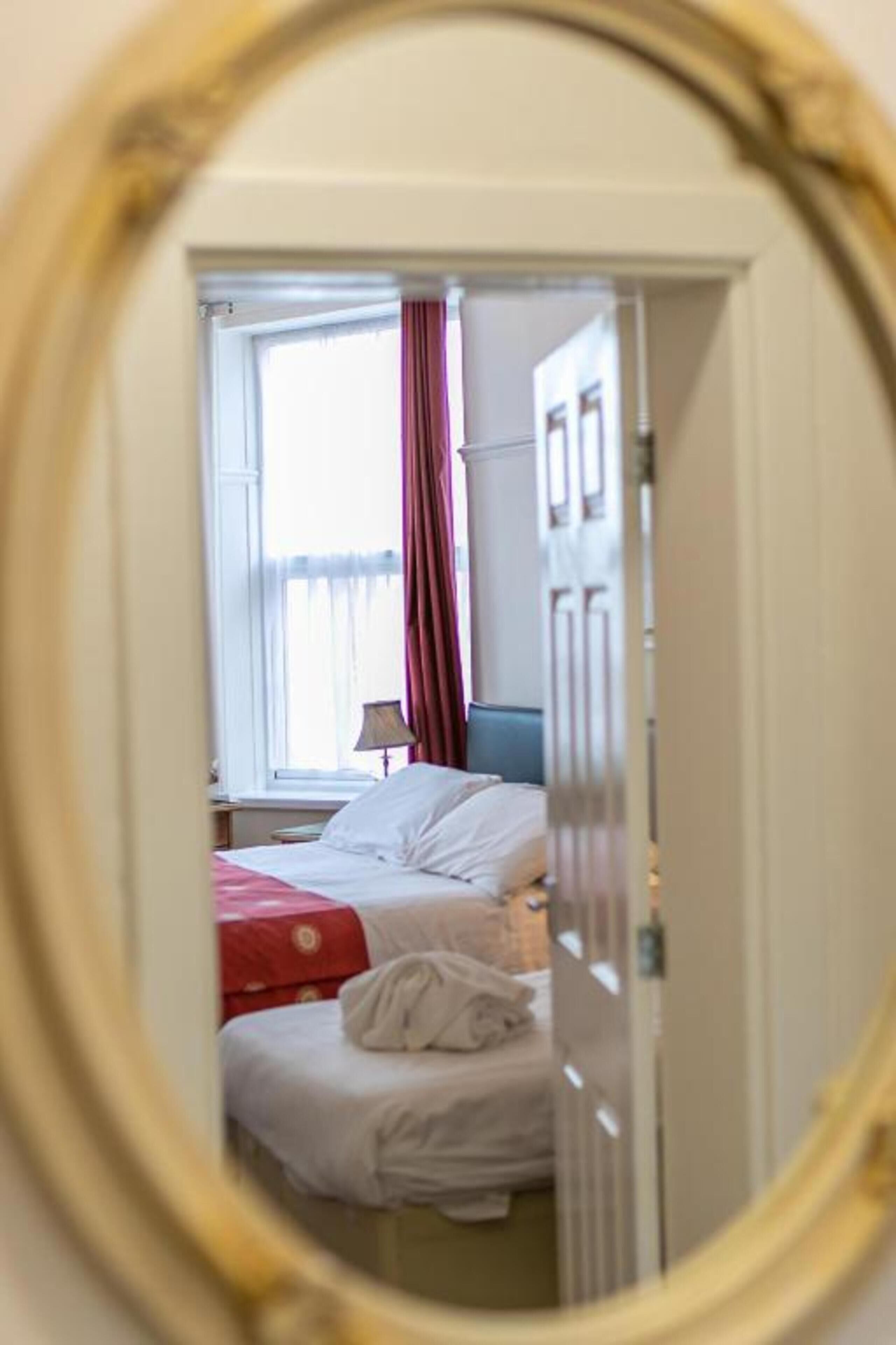 Une chambre avec deux lits, une fenêtre avec des rideaux et une porte.