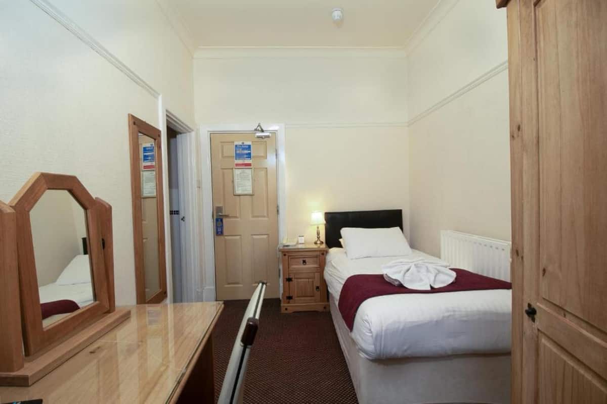 Une chambre d’hôtel avec un lit, une table de chevet, une lampe et un miroir.
