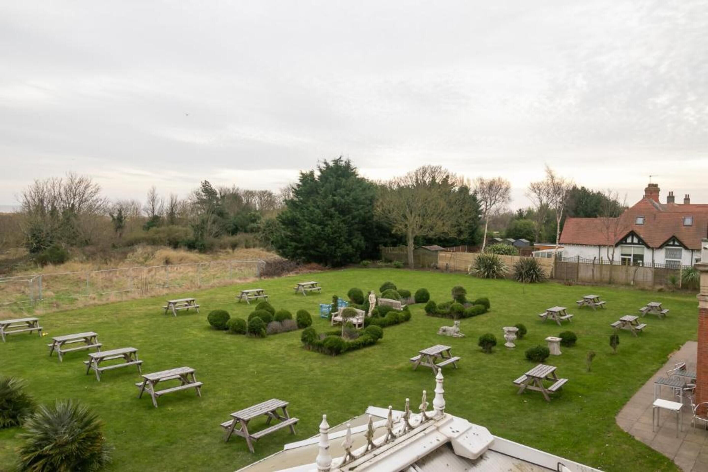 A well-maintained garden with picnic tables and neatly trimmed hedges.