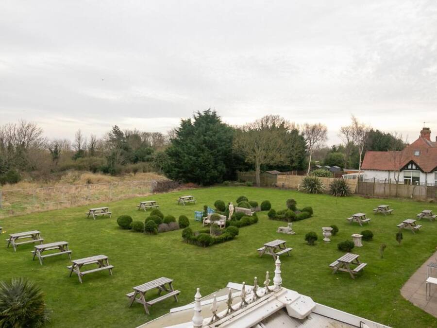 Een verzorgde tuin met picknicktafels en strakke haagjes.