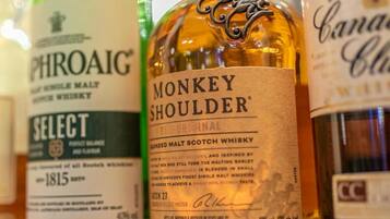 Uma seleção de garrafas de whisky, incluindo marcas como PHROAIG, MONKEY SHOULDER e CANADA CLUB.