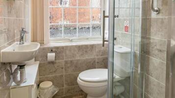 A modern bathroom with a glass-enclosed shower, a sink, and a toilet.