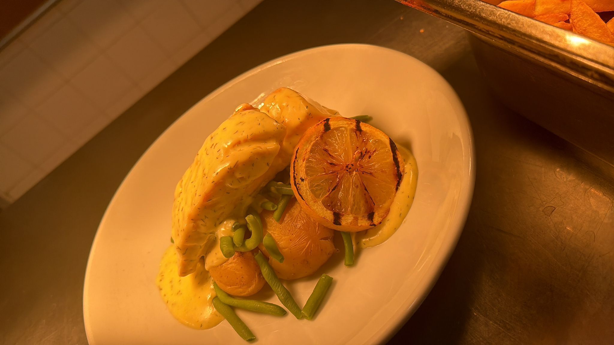 A plate with chicken, green beans, and a grilled orange slice.
