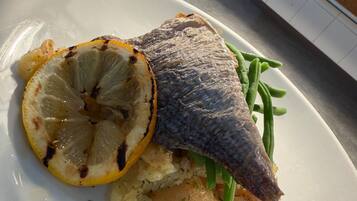 Un plato con pescado, una rodaja de limón y judías verdes.