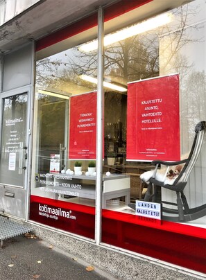 A hotel window with red signage and a chair with stuffed animals.