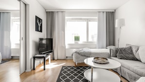 Ein modernes Wohnzimmer mit einer Couch, einem Couchtisch, einem Fernseher und einem Bett.