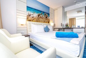 A modern hotel room with a large bed, a seating area, and a wall-mounted TV. - Mera Onix Cap Aurora (Cap Aurora)