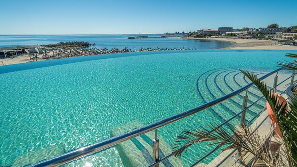 A clear blue pool with a view of the beach and ocean. - Mera Onix Cap Aurora (Cap Aurora)