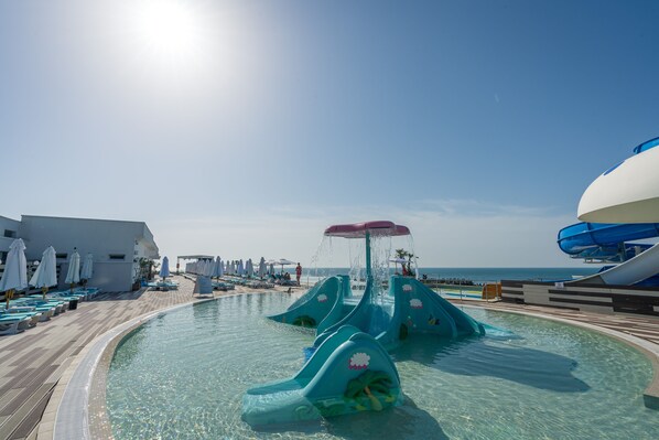 A pool area with water slides and lounge chairs.