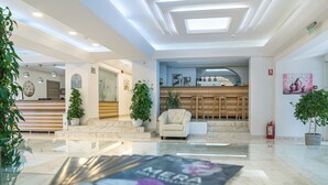 A modern lobby with a reception desk, seating area, and a kitchen in the background. - Mera Brise (Mangalia)