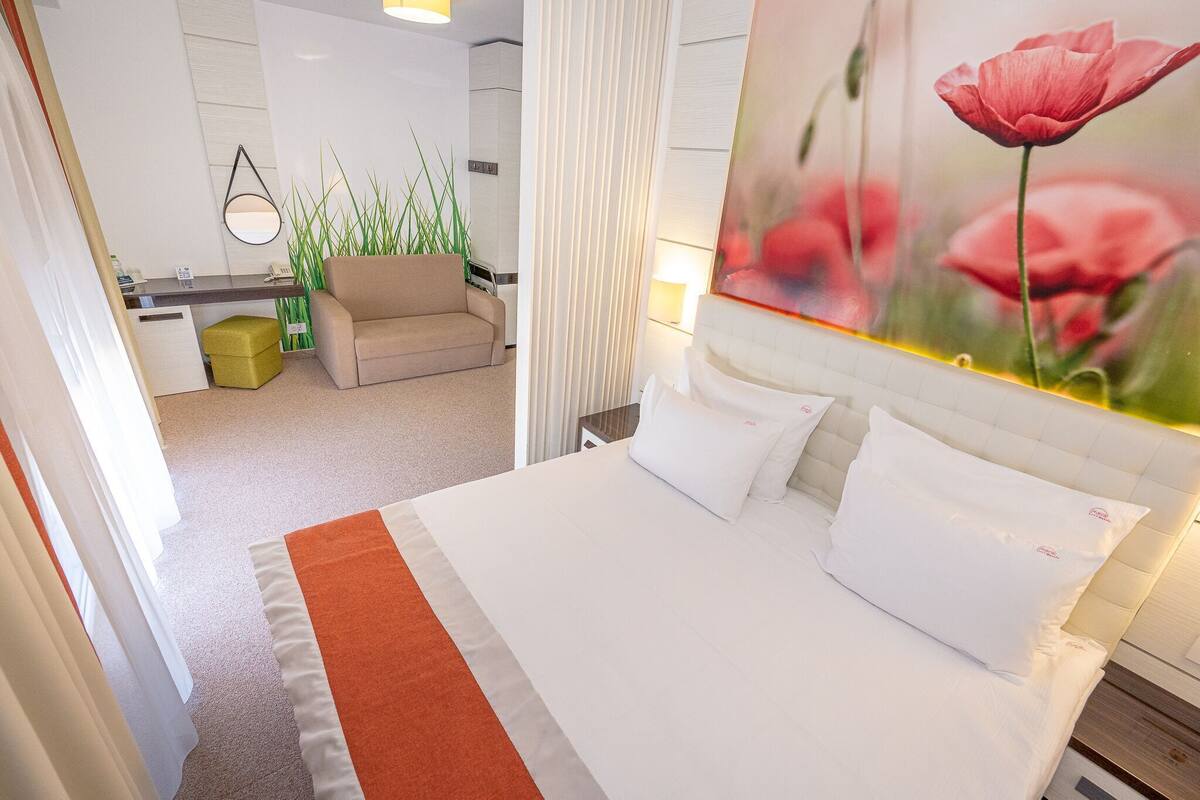 A hotel room with a bed, a desk, a chair, and a large window.