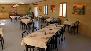 Un comedor con varias mesas dispuestas para comidas, sillas e iluminación colgante.