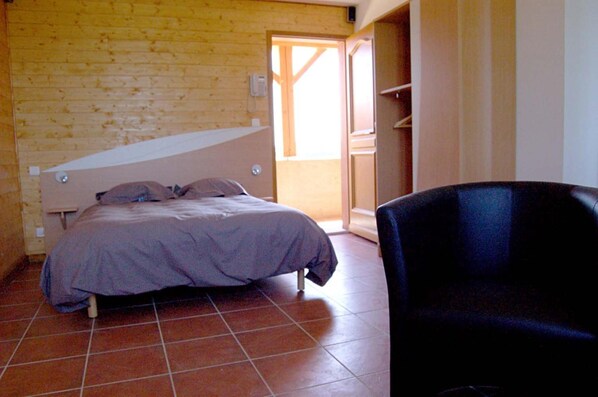 Un dormitorio con una cama, una silla y una pared de madera.