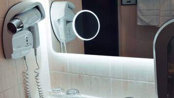 A bathroom with a sink, a mirror, a hairdryer, and a towel rack.
