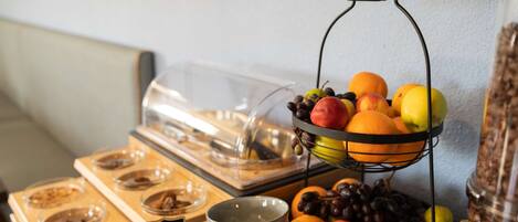 A buffet setup with a fruit display, bowls, and a coffee station.