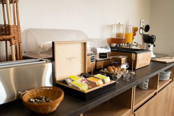 A breakfast buffet setup with various food items, a coffee machine, and a toaster. - Brit Hotel Confort La Tour Blanche (Saint-Yrieix-la-Perche)