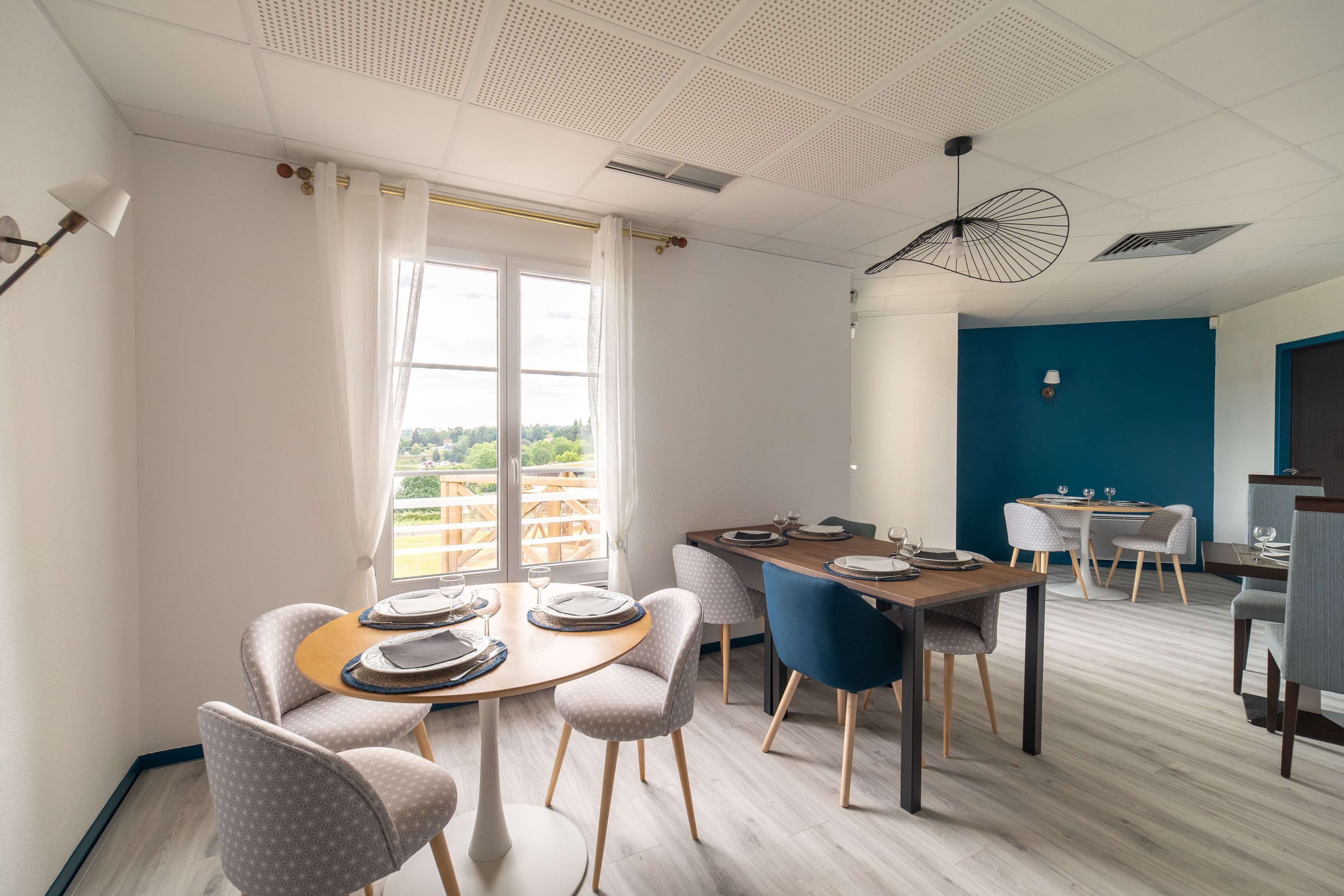 A modern dining area with round tables, chairs, and a view of the outdoors.