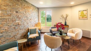 Een modern interieur met een stenen muur, een groot raam en een zithoek met een tafel en stoelen.