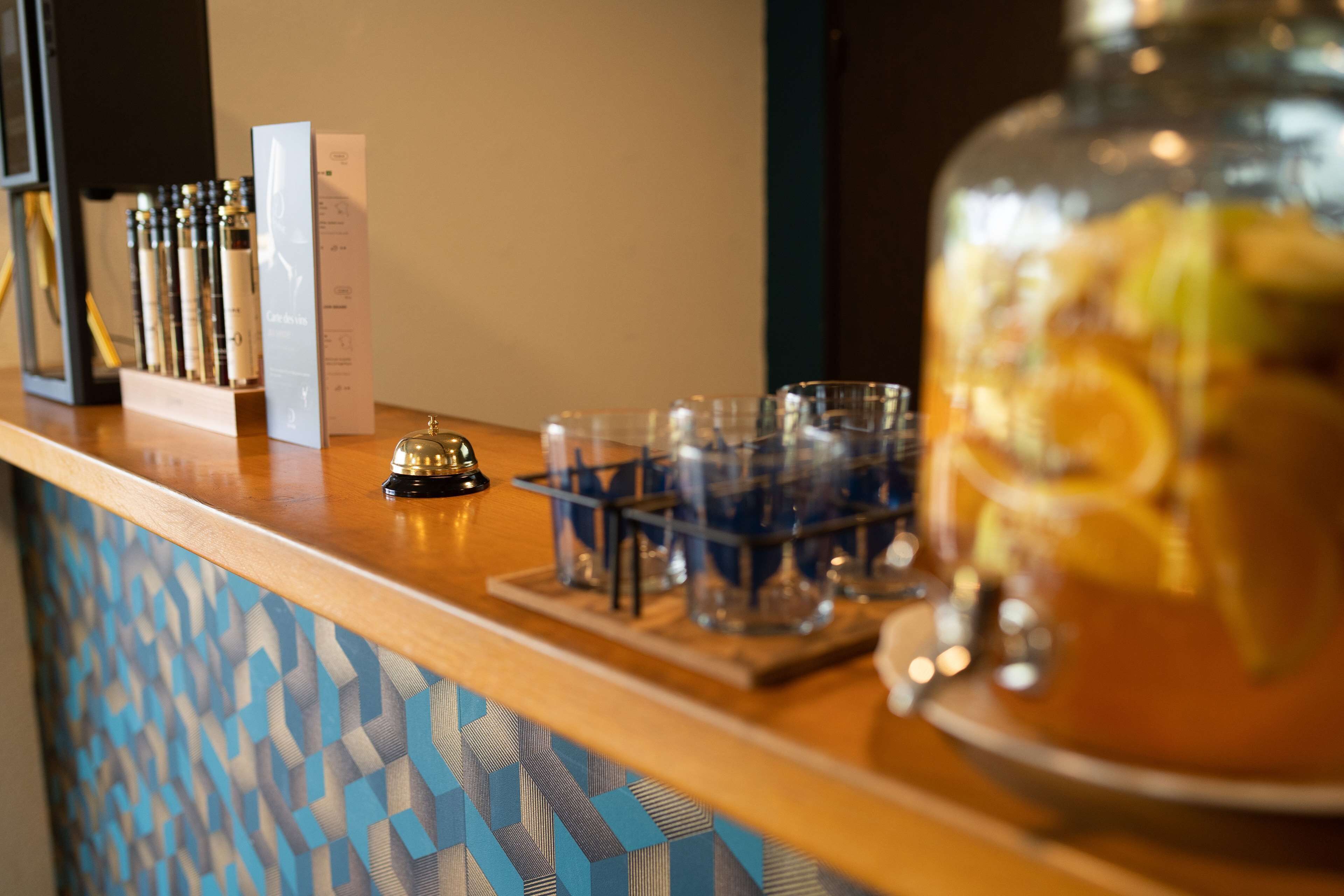 A bar area with a glass jar filled with fruit, a bottle of liquor, and a tray of glasses.