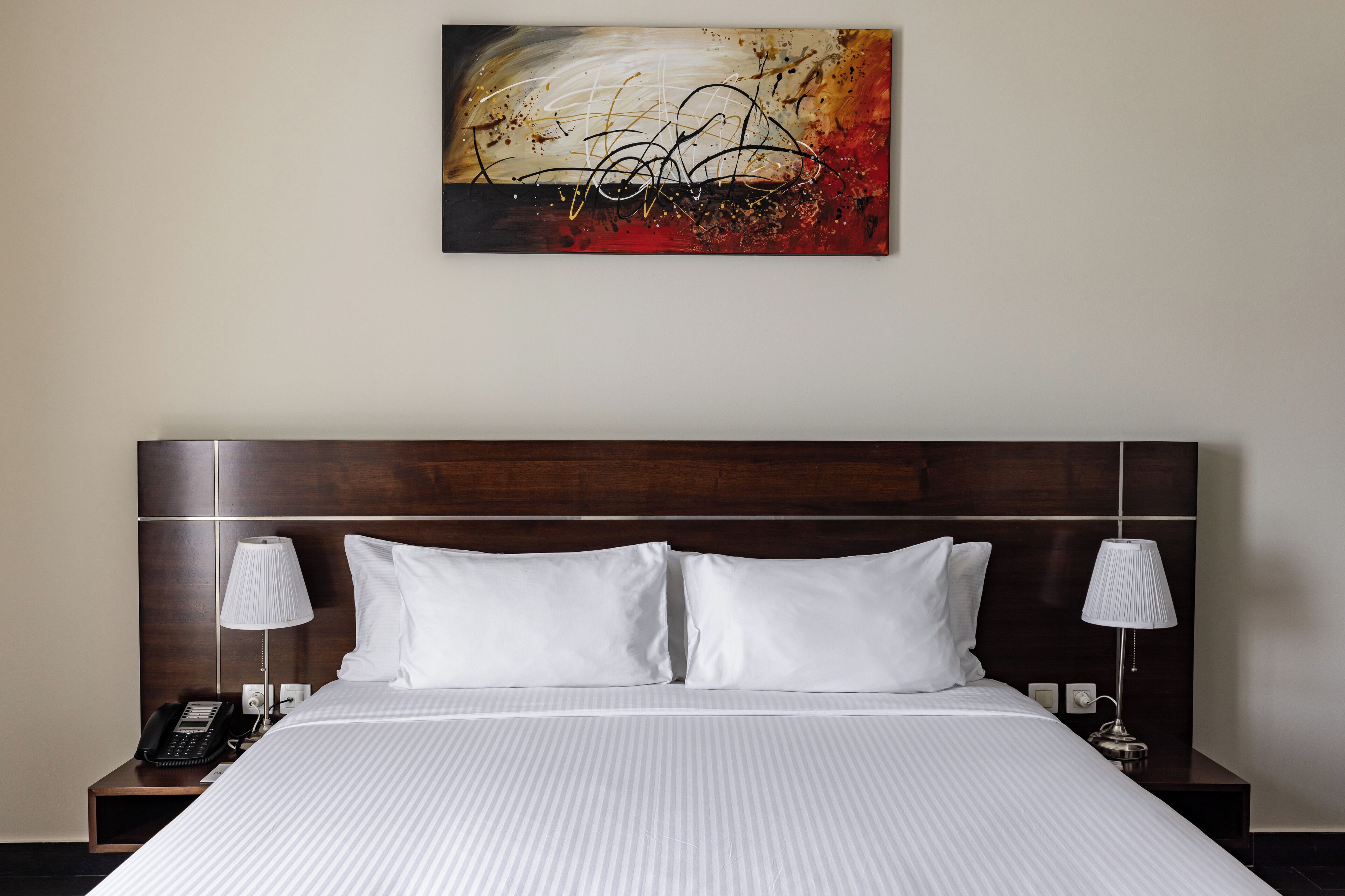 Habitación de hotel con una cama grande, dos mesitas de noche, un teléfono y una lámpara a cada lado.