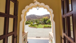 An entrance with a decorative archway leading to a courtyard with a view of a hill and greenery. - WelcomHeritage Mount Valley Resort, Ranthambore (Sawai Madhopur)