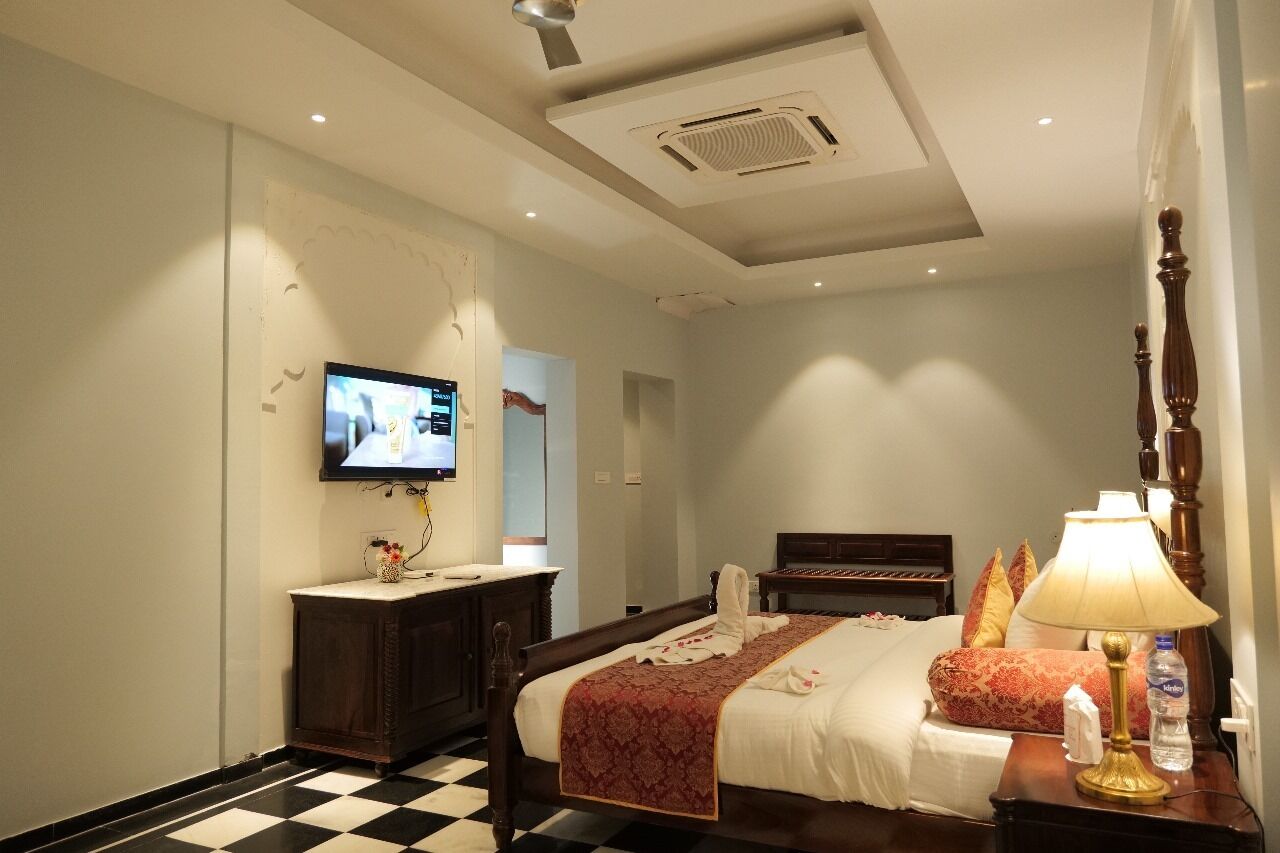 A hotel room with a bed, a television, a nightstand, and a checkered floor.