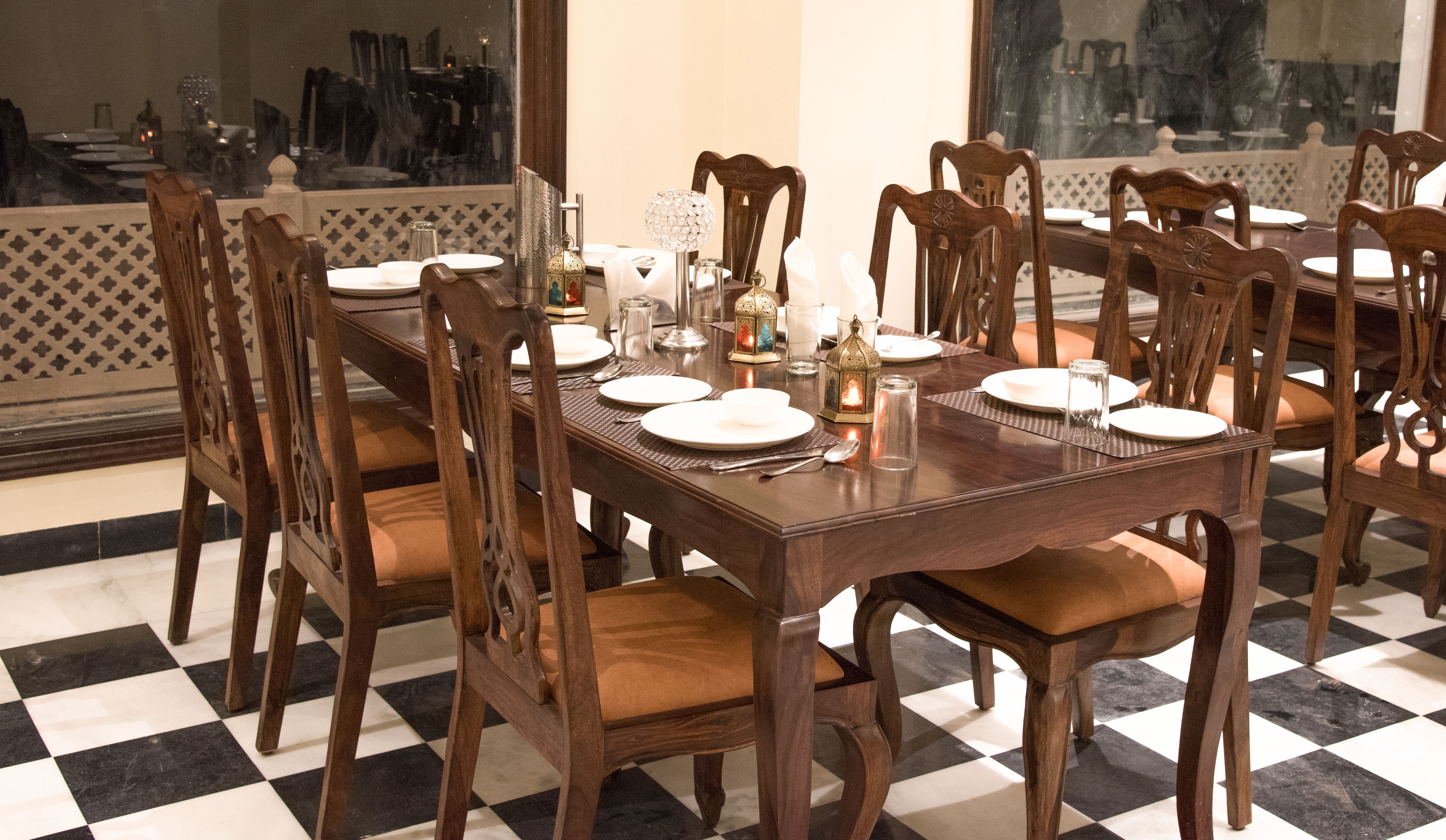 A dining area with a checkered floor, wooden chairs, and a table set for a meal.