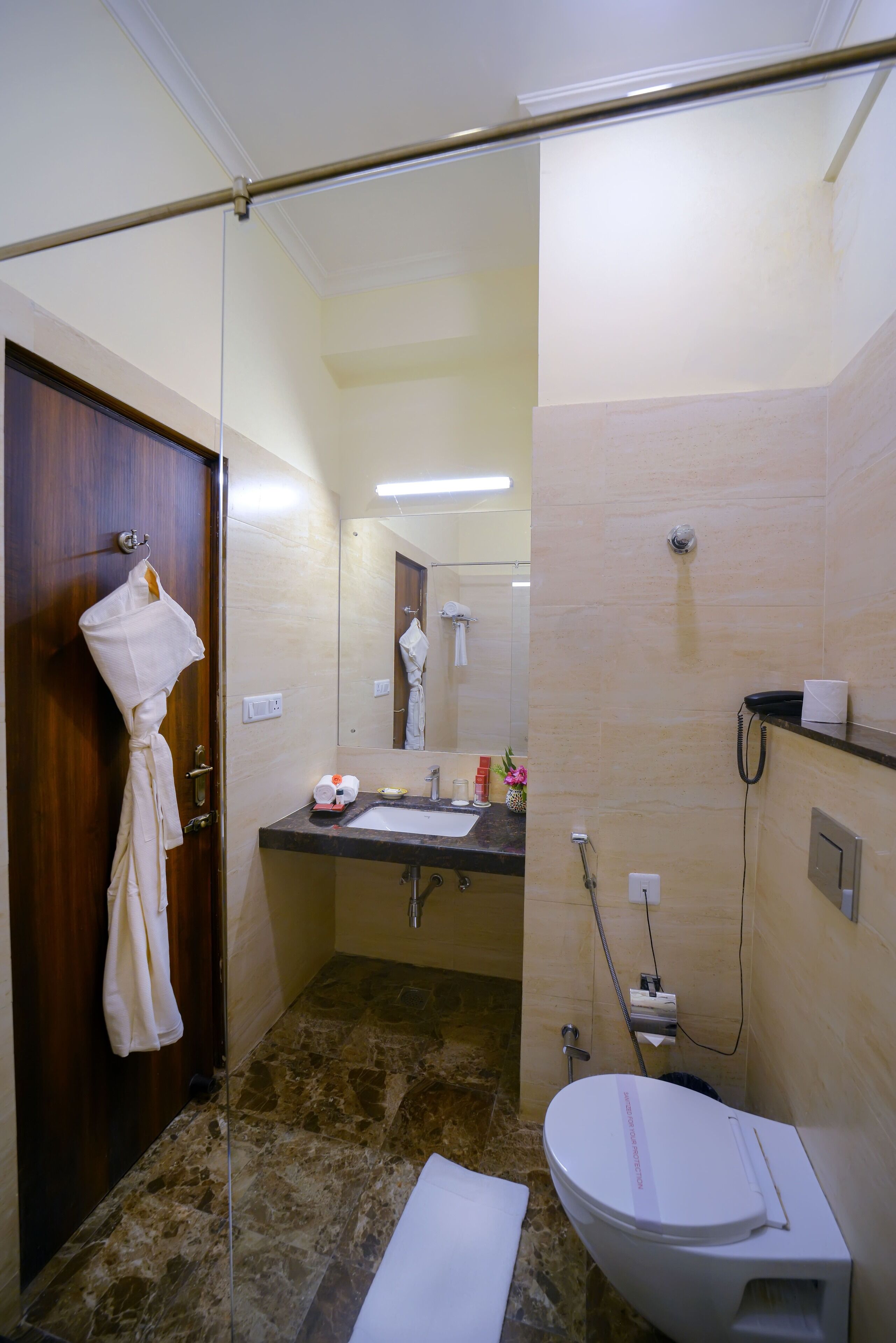 Un baño con puerta de madera, un lavabo, un espejo, un inodoro y una zona de ducha.