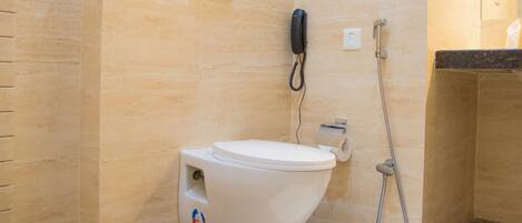 A modern bathroom with a toilet, a handheld shower, and a towel rack.