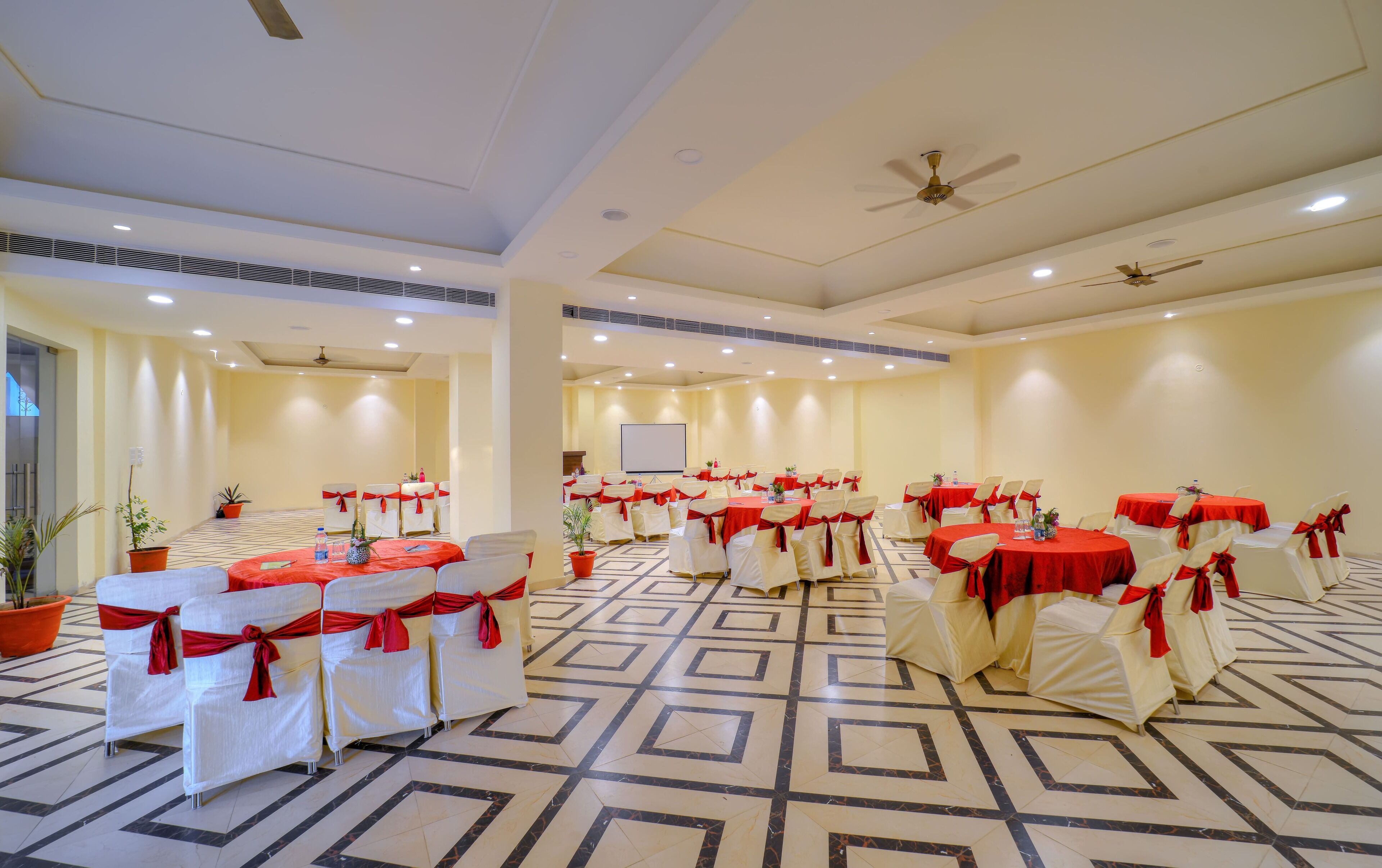 A conference room with multiple tables, chairs, and ceiling fans.