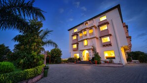 A multi-story hotel with a traditional architectural style, featuring a central entrance with steps and a balcony. - WelcomHeritage Mount Valley Resort, Ranthambore (Sawai Madhopur)