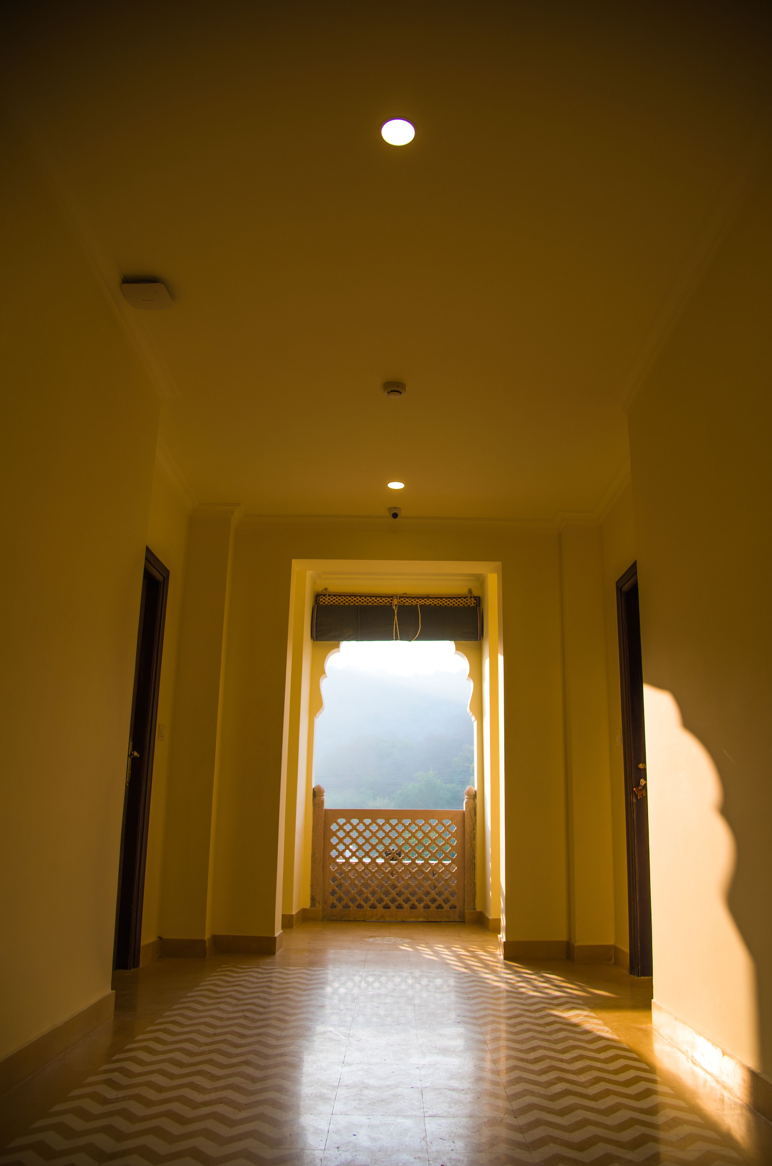 A hallway with patterned flooring leading to a balcony with a lattice gate.