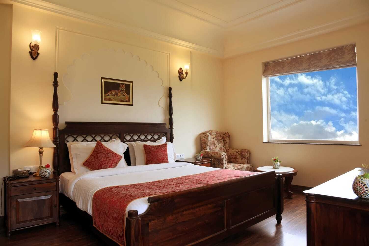 Une chambre à coucher bien aménagée, avec un lit à baldaquin, une chaise, une petite table et une grande fenêtre donnant sur le ciel.