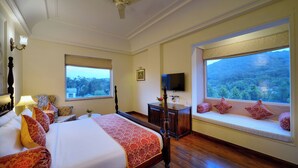 A hotel room with a large bed, a desk, a television, and windows with scenic views. - WelcomHeritage Mount Valley Resort, Ranthambore (Sawai Madhopur)