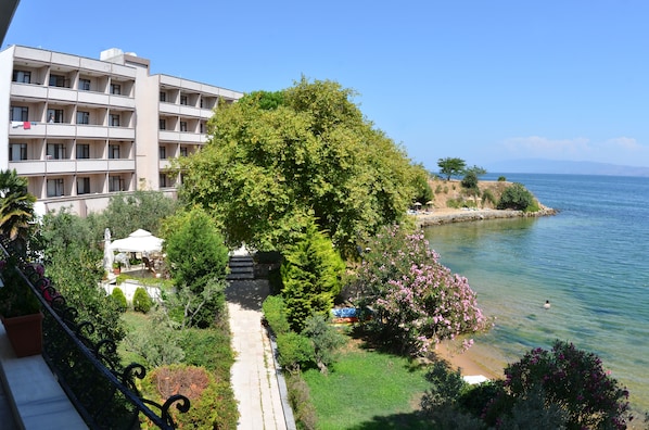 Un hotel con vista a un lago, un jardín con un sendero y un edificio con varios balcones.