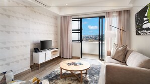 A modern living room with a sofa, a coffee table, a TV, and a balcony with a city view.
