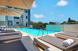 A rooftop pool area with lounge chairs and umbrellas. - The Regency Apartment Hotel Menlyn (Pretoria)
