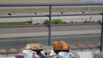 Una mesa en el balcón con vista a la playa y al océano.