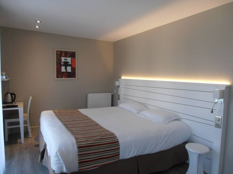 Habitación de hotel moderna con una cama grande, una mesita de noche, una silla y un calentador de pared.
