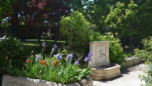 A garden with a stone planter filled with flowers and a stone bench.