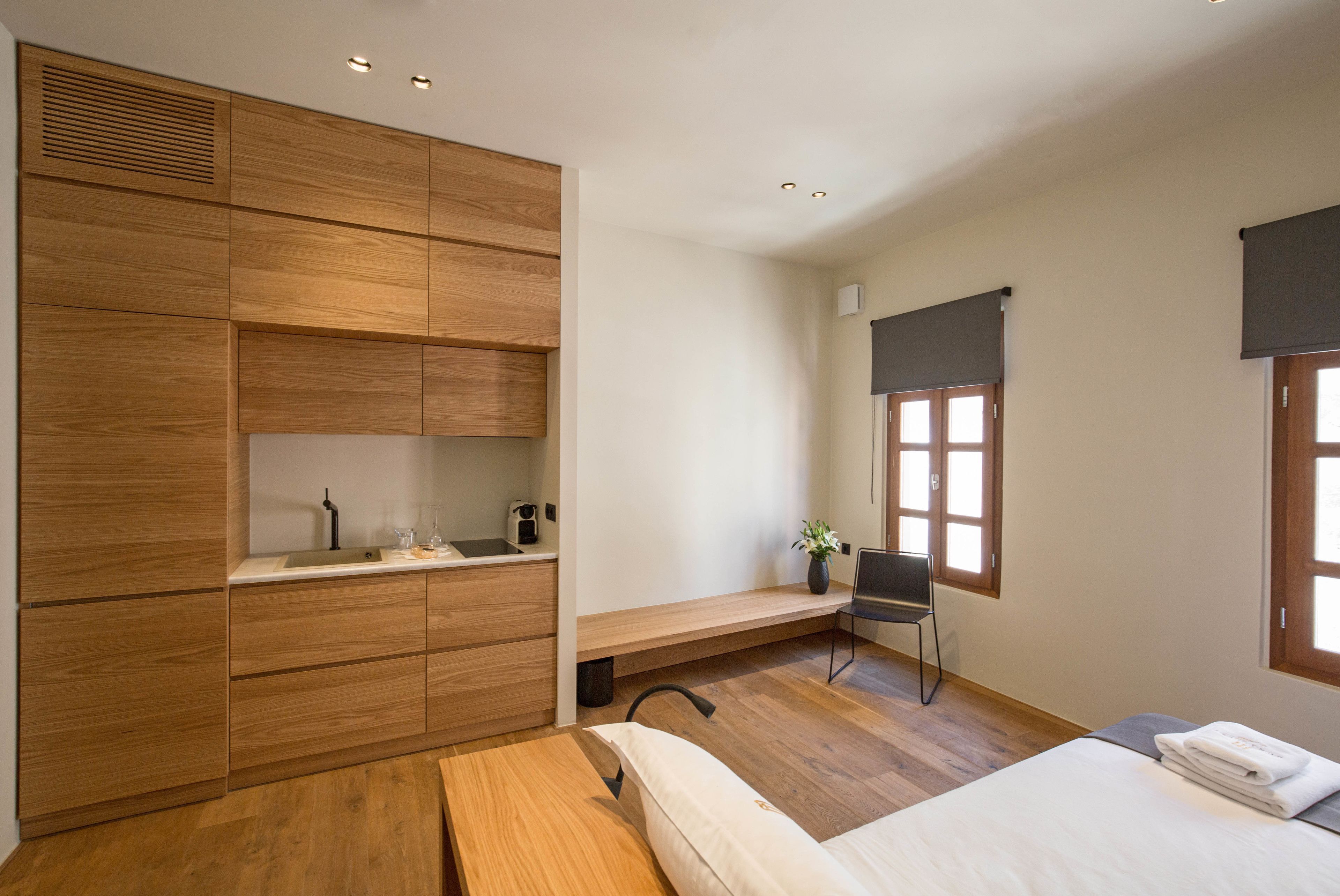 A modern bedroom with a wooden wardrobe, a bedside table, a chair, and a bed.