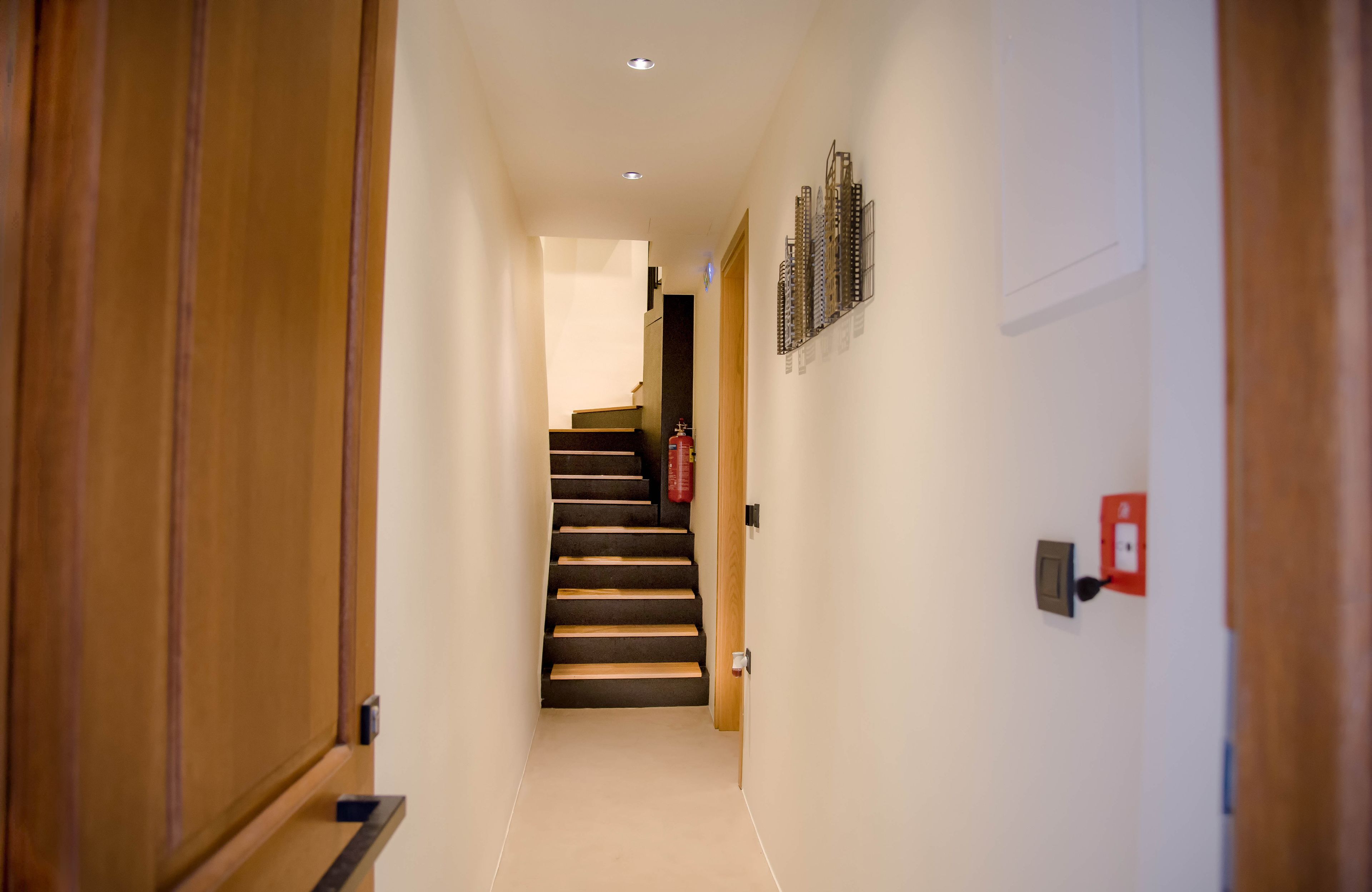A narrow hallway with wooden doors and a staircase leading to a landing.