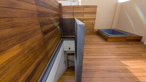 A modern bathroom with wooden paneling, a shower area, and a bathtub.