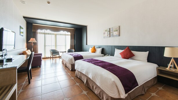 A hotel room with two beds, a desk, a chair, and a window with curtains. - Kenting Kaiying Hotel (Hengchun)
