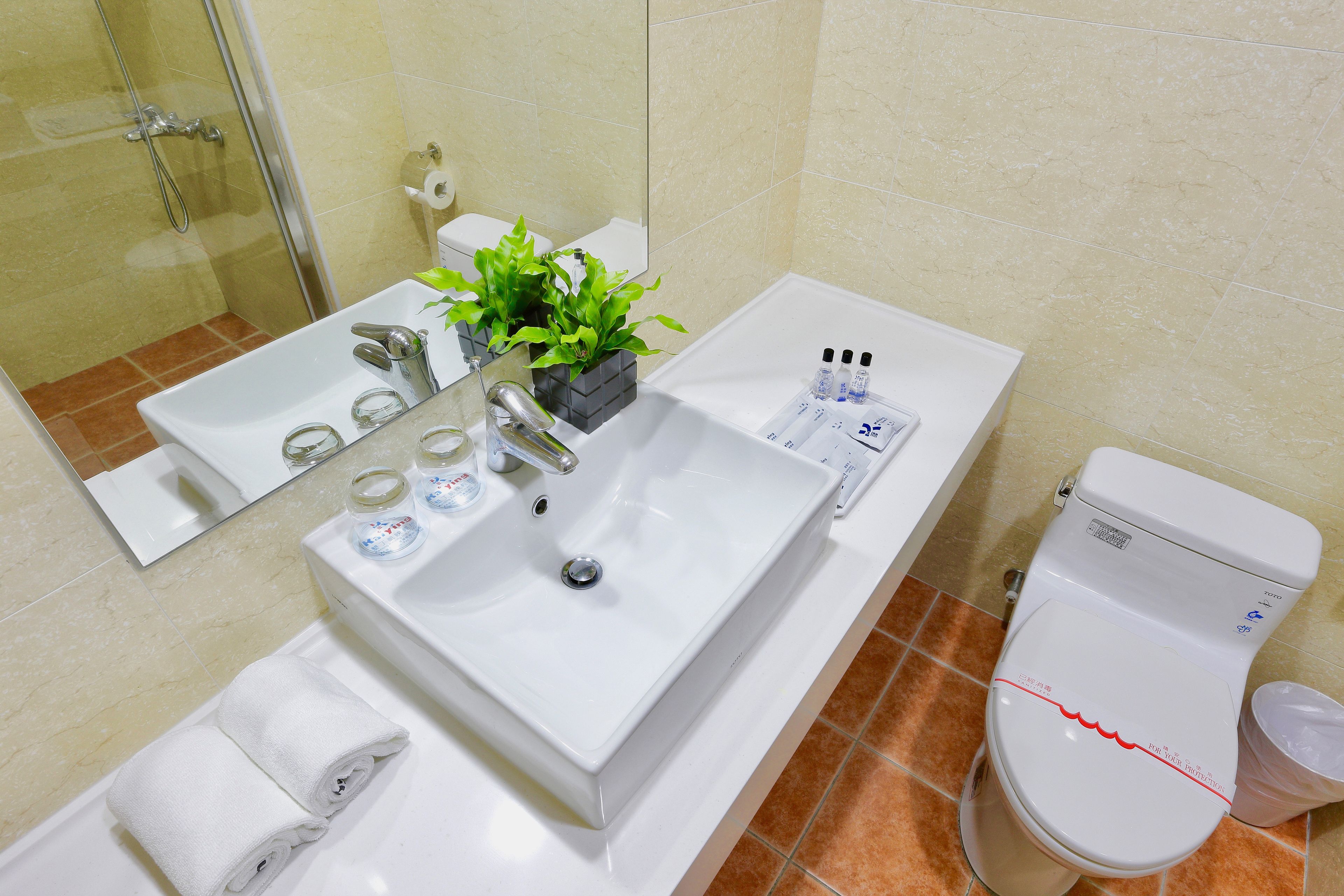 A modern bathroom with a white sink, mirror, and toilet.