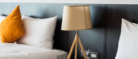 Una habitación de hotel con una cama, una lámpara y dos cuadros en la pared.