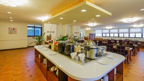 A spacious dining area with a long counter, multiple tables, and a view of the city through large windows. - Kenting Kaiying Hotel (Hengchun)