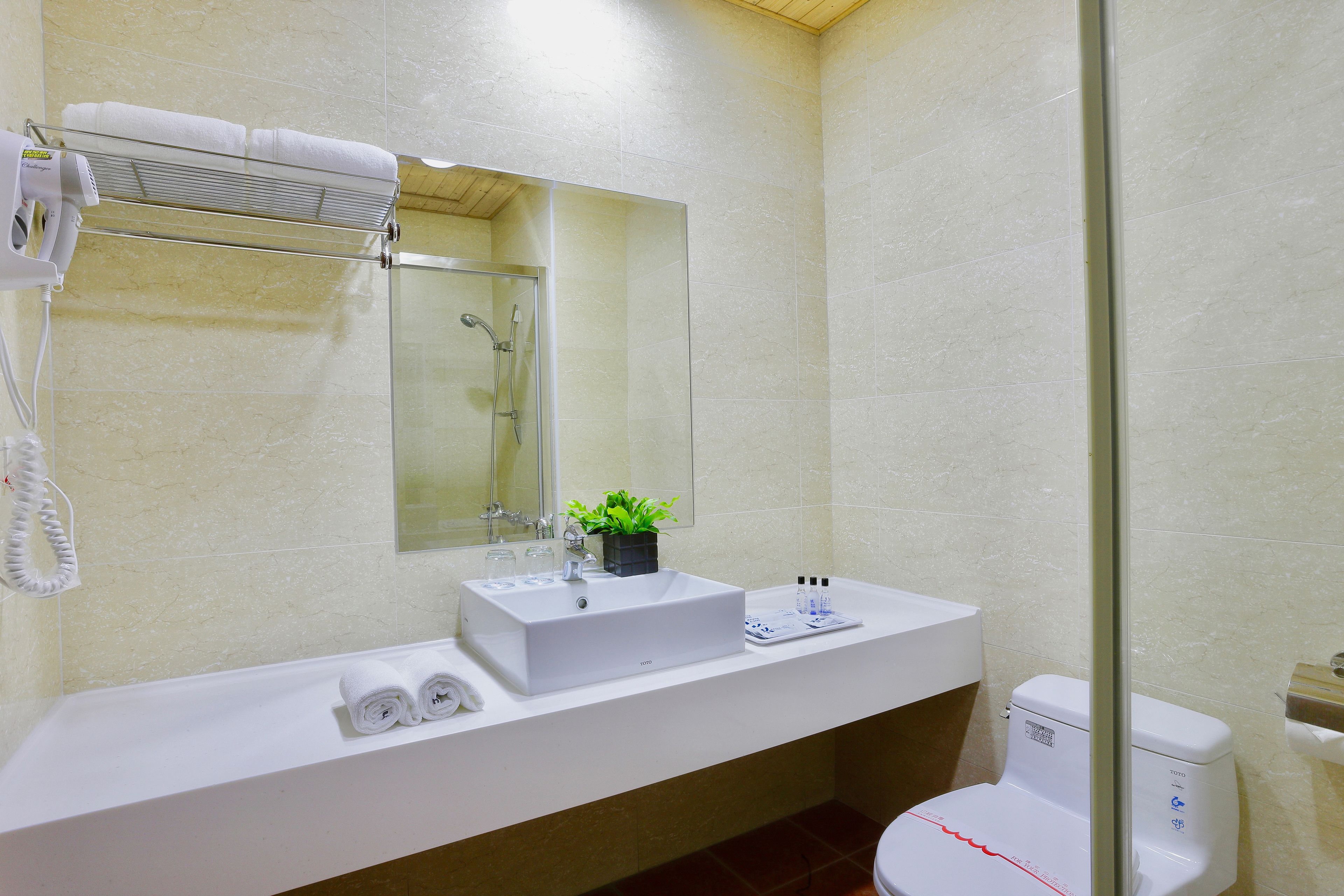 A modern bathroom with a white sink, a glass shower enclosure, and a toilet.